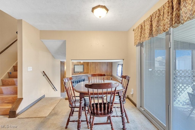 dining area with stairs, baseboards, a textured ceiling, and light colored carpet