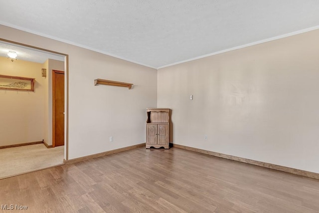 unfurnished room featuring crown molding, baseboards, and wood finished floors