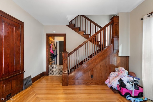 foyer entrance featuring stairway, baseboards, visible vents, and wood finished floors