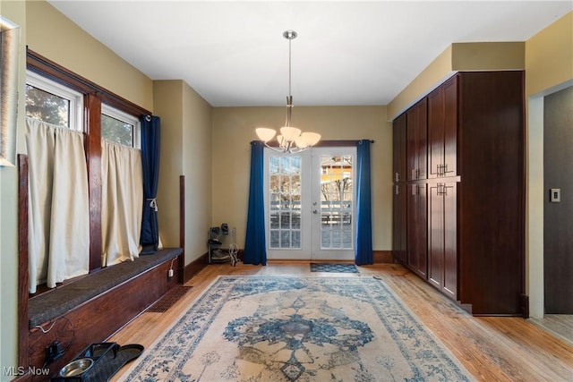 interior space with a chandelier, light wood-type flooring, french doors, and plenty of natural light