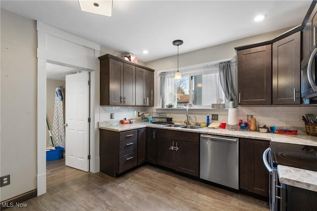 kitchen featuring dark brown cabinetry, tasteful backsplash, appliances with stainless steel finishes, light wood-style floors, and a sink