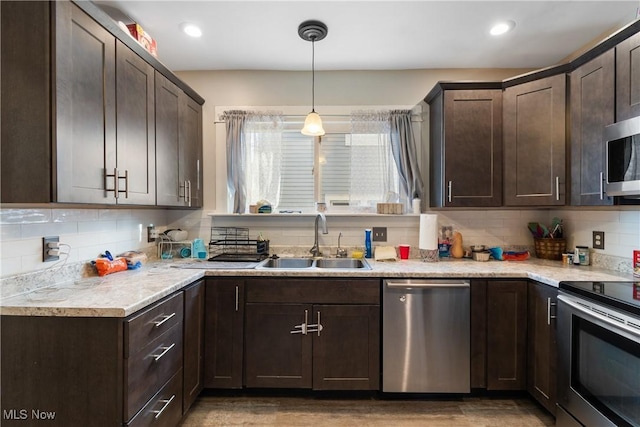 kitchen featuring appliances with stainless steel finishes, a sink, dark brown cabinets, and tasteful backsplash