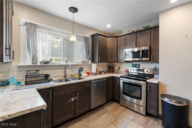 kitchen featuring stainless steel appliances, backsplash, a sink, and dark brown cabinetry