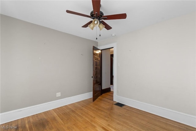 spare room with light wood-style floors, visible vents, baseboards, and a ceiling fan