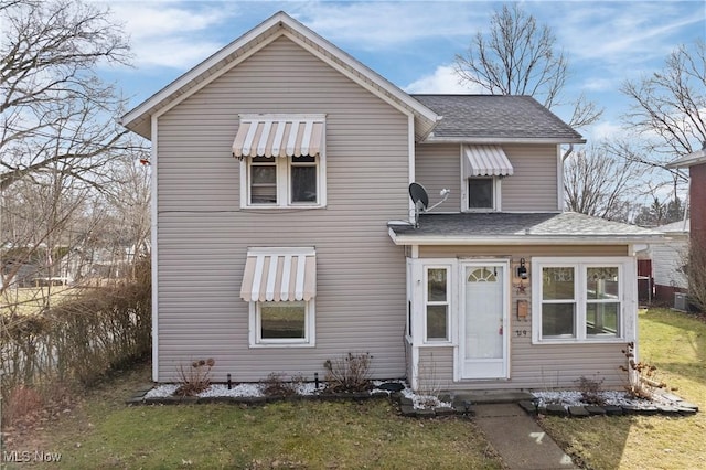 traditional-style house featuring central AC unit, a front lawn, and roof with shingles