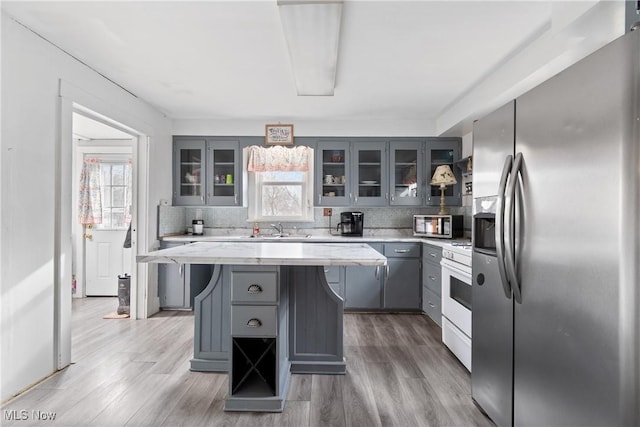 kitchen with light wood-type flooring, gray cabinets, stainless steel appliances, and a sink