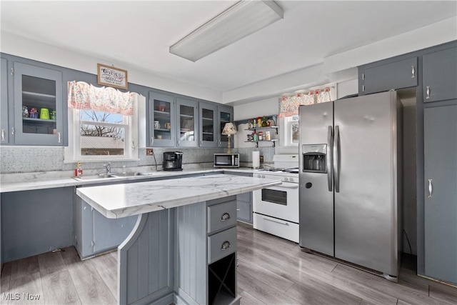 kitchen with appliances with stainless steel finishes, a sink, gray cabinetry, and open shelves