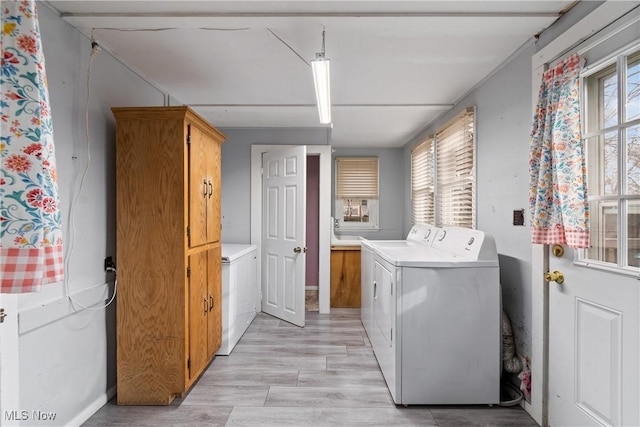 clothes washing area with light wood finished floors and washing machine and dryer