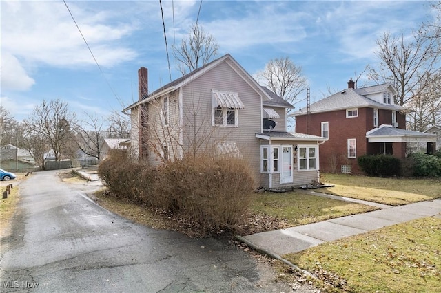 view of front of house with a chimney and a front lawn