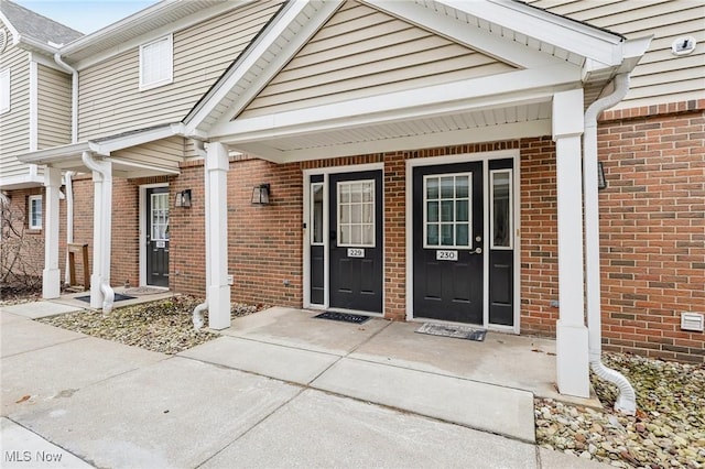 entrance to property with a porch and brick siding