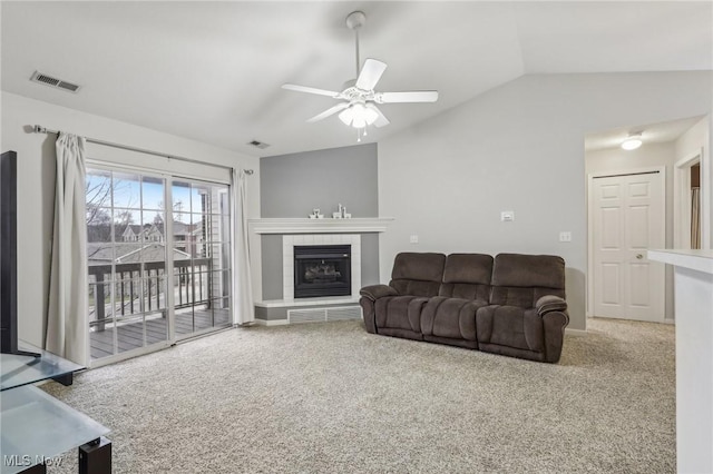 living area with lofted ceiling, visible vents, carpet floors, and a tiled fireplace