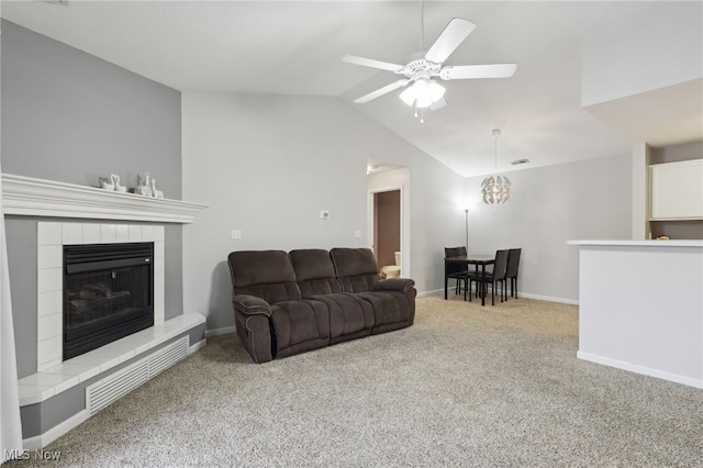 living area featuring baseboards, a tile fireplace, ceiling fan, carpet, and vaulted ceiling