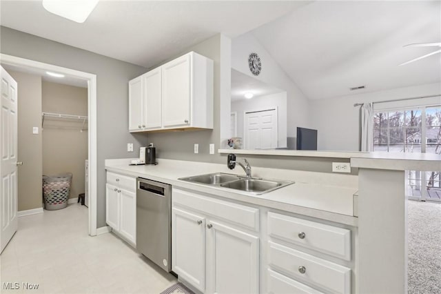 kitchen with white cabinets, light countertops, a sink, and stainless steel dishwasher