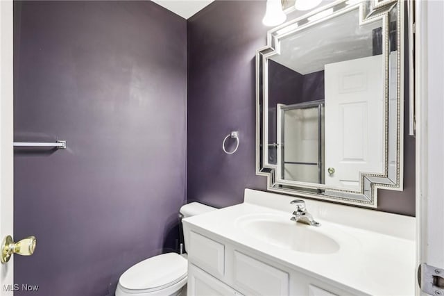 full bathroom with an enclosed shower, vanity, and toilet