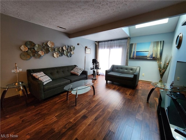 living area with visible vents, a textured ceiling, baseboards, and wood finished floors