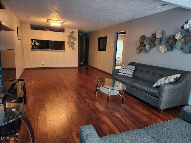 living area featuring a textured ceiling, baseboards, and wood finished floors