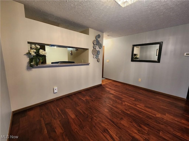 unfurnished room featuring a textured ceiling, baseboards, and wood finished floors