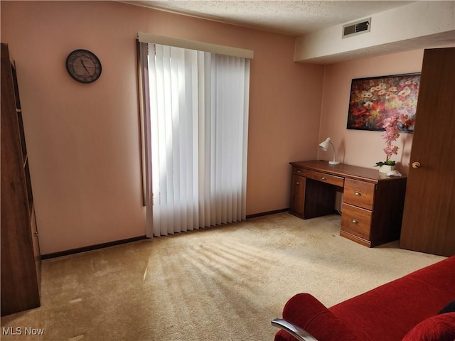 office space featuring a textured ceiling, baseboards, visible vents, and light colored carpet