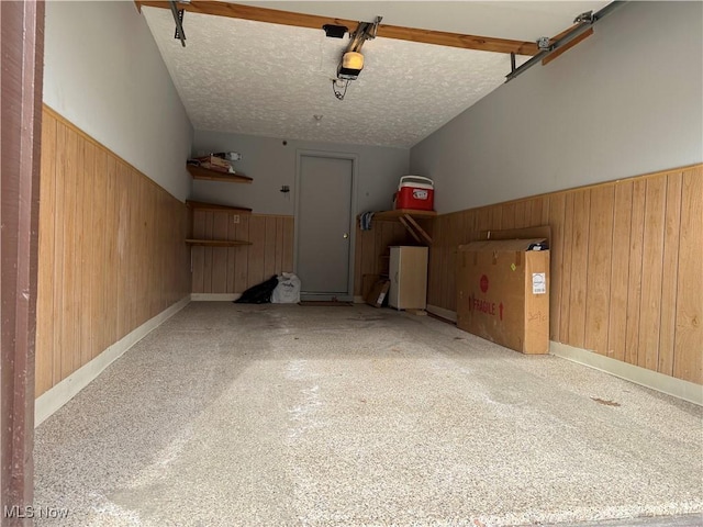 garage with a garage door opener, wainscoting, and wood walls