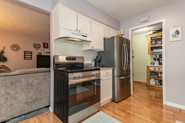 kitchen with light wood finished floors, appliances with stainless steel finishes, under cabinet range hood, white cabinetry, and backsplash