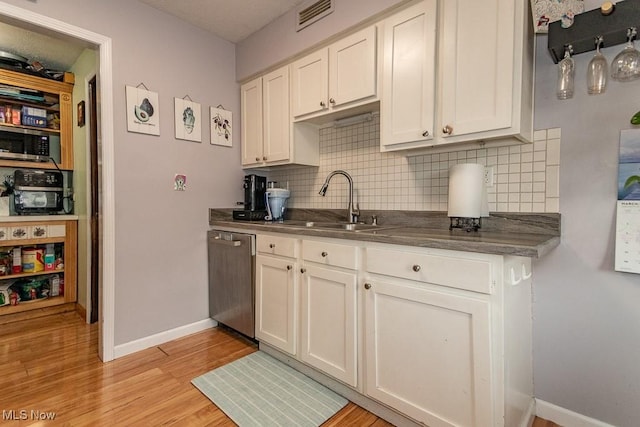 kitchen with light wood finished floors, visible vents, dark countertops, appliances with stainless steel finishes, and a sink