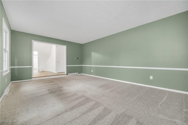 empty room with carpet flooring, visible vents, and baseboards