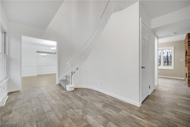 interior space featuring an inviting chandelier, stairs, baseboards, and wood finished floors