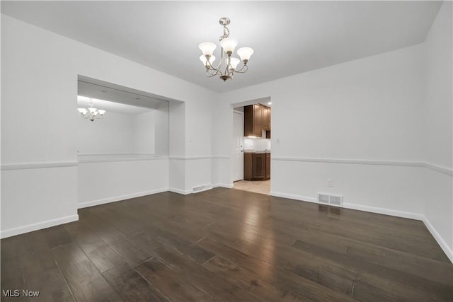 unfurnished dining area featuring an inviting chandelier, baseboards, visible vents, and wood finished floors