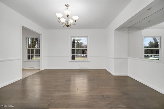 empty room featuring baseboards, visible vents, an inviting chandelier, and wood finished floors