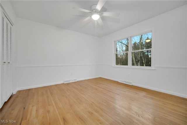 empty room with light wood finished floors, baseboards, visible vents, and ceiling fan