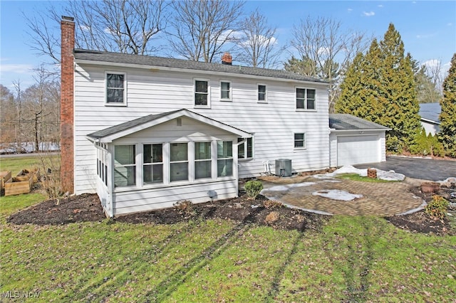 rear view of house featuring driveway, a yard, a chimney, and central air condition unit