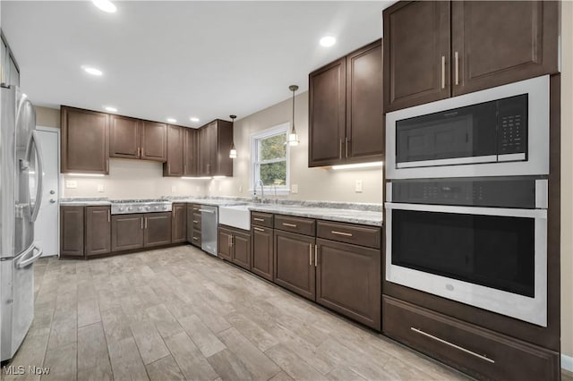 kitchen featuring dark brown cabinetry, recessed lighting, stainless steel appliances, a sink, and decorative light fixtures