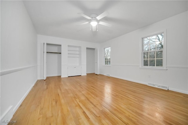 unfurnished bedroom featuring radiator, light wood finished floors, baseboards, and visible vents