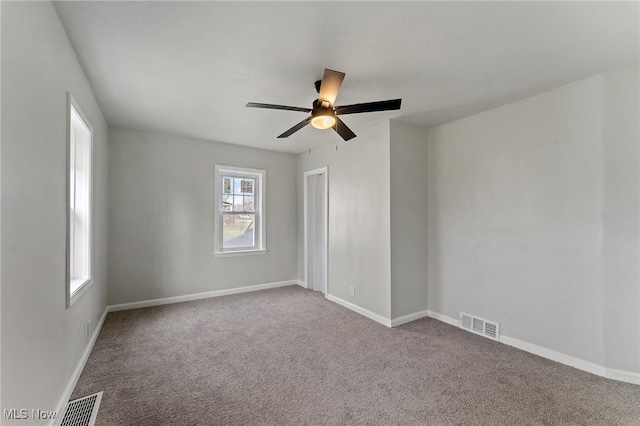 spare room featuring carpet, visible vents, ceiling fan, and baseboards