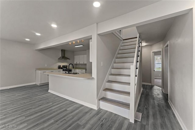 kitchen with dark wood finished floors, white cabinets, light countertops, wall chimney range hood, and recessed lighting