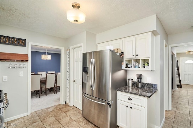 kitchen featuring light tile patterned floors, a textured ceiling, white cabinetry, stainless steel fridge with ice dispenser, and dark stone counters