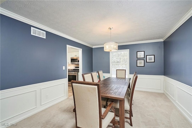 dining room with ornamental molding, visible vents, light carpet, and a textured ceiling