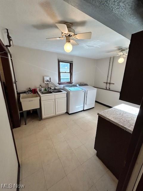 laundry area featuring cabinet space, a ceiling fan, a sink, and washing machine and clothes dryer