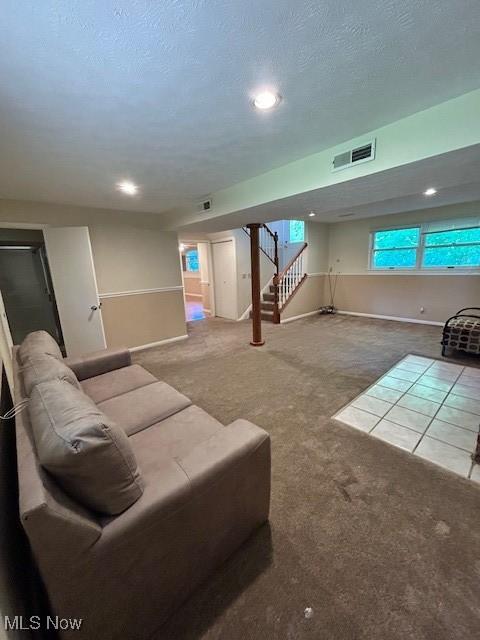 carpeted living room featuring visible vents, a textured ceiling, baseboards, and stairs