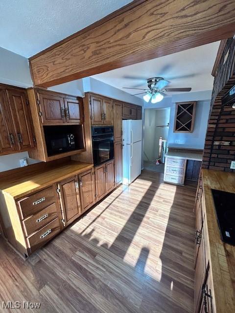 kitchen with black appliances, a ceiling fan, brown cabinetry, and dark wood-type flooring