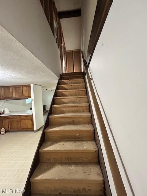 stairway featuring a textured ceiling