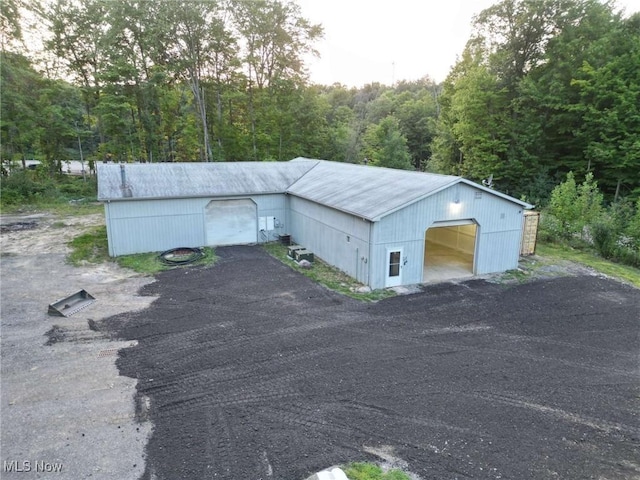 exterior space featuring a garage, an outdoor structure, and a wooded view