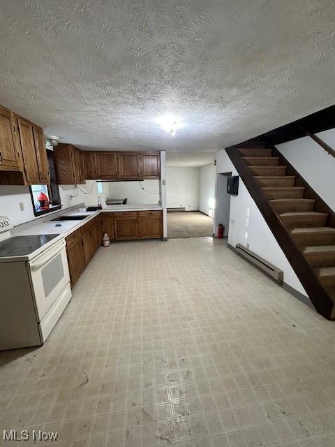 kitchen featuring electric stove, light floors, light countertops, baseboard heating, and brown cabinetry