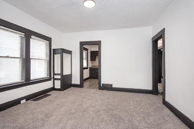 unfurnished room featuring carpet flooring, visible vents, and baseboards