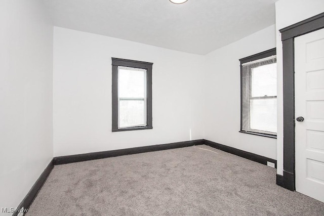 empty room featuring baseboards and carpet flooring