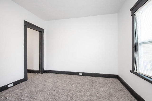 carpeted spare room featuring baseboards