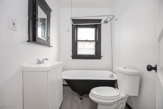 bathroom with toilet, wood finished floors, a freestanding bath, and vanity