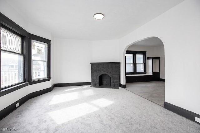 unfurnished living room with a fireplace, baseboards, and carpet flooring