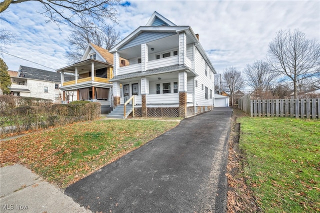 view of front of property featuring an outbuilding, a porch, a front yard, fence, and a balcony