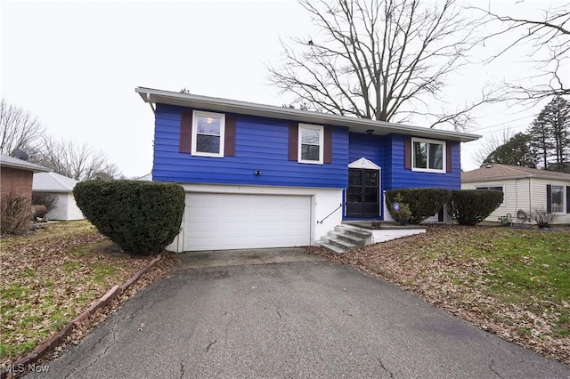 split foyer home featuring a garage and aphalt driveway